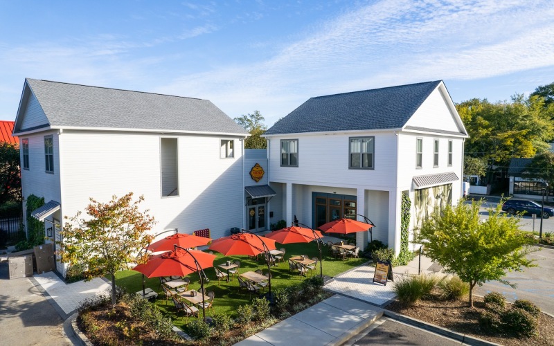 two story white buildings with a patio and red umbrellas