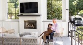 a person and dog on a porch with a fireplace and tv 